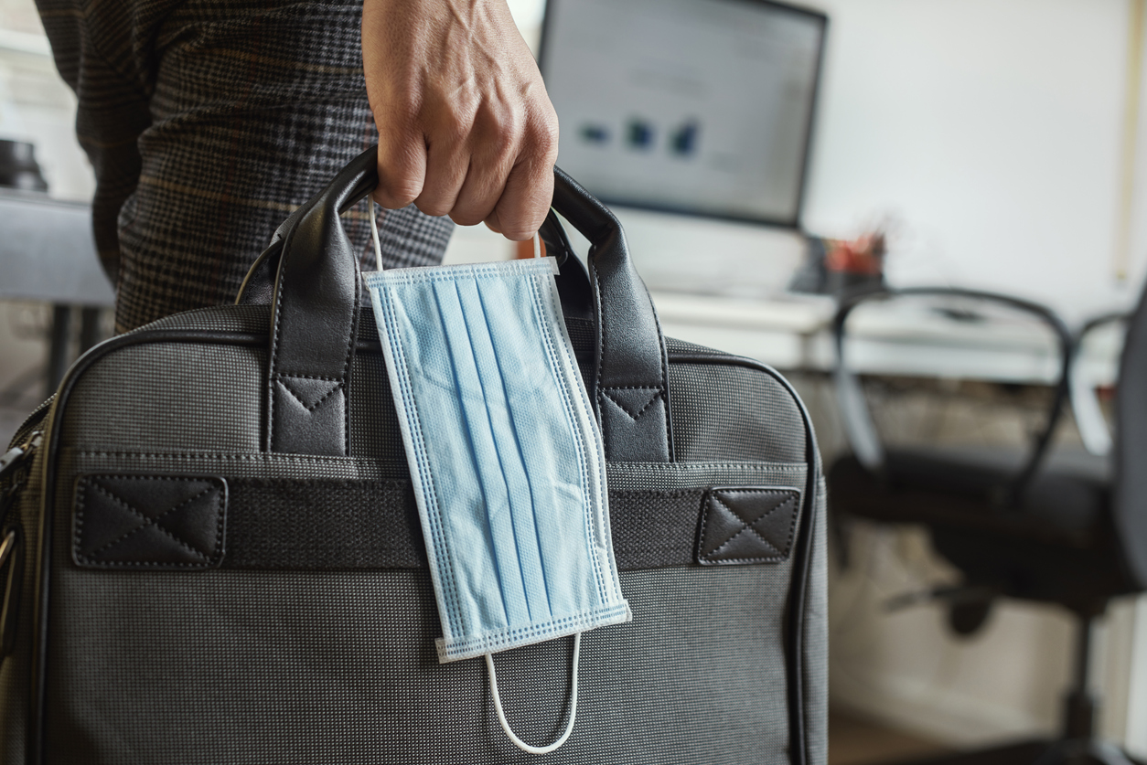 Man carrying a briefcase and a mask