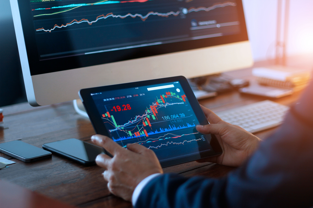 Businessman checking stocks on a computer and a tablet