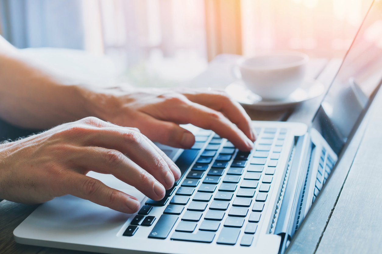 A man's hands typing on a laptop keyboard