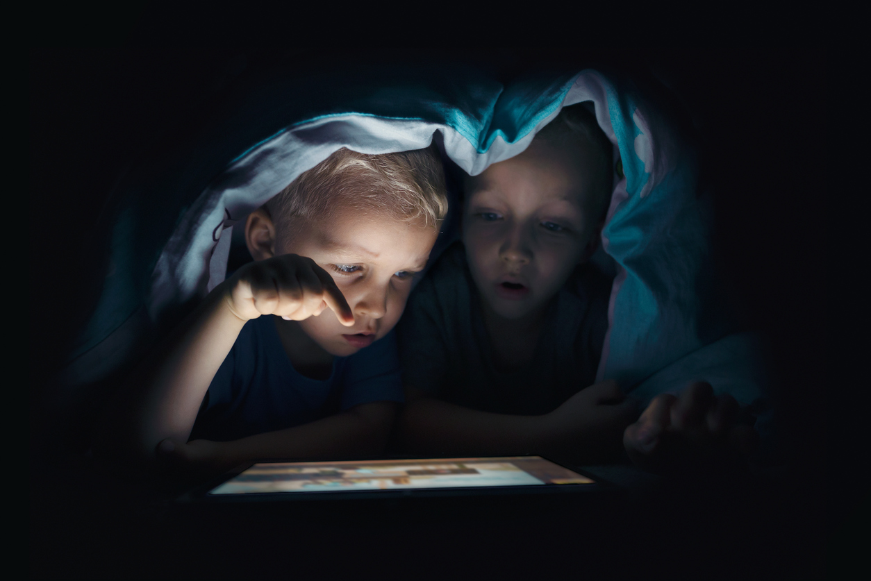 Two kids with tablet computer in a dark room