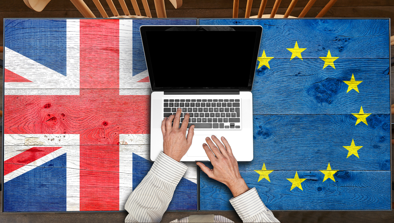 Laptop on European and UK flagged wooden table