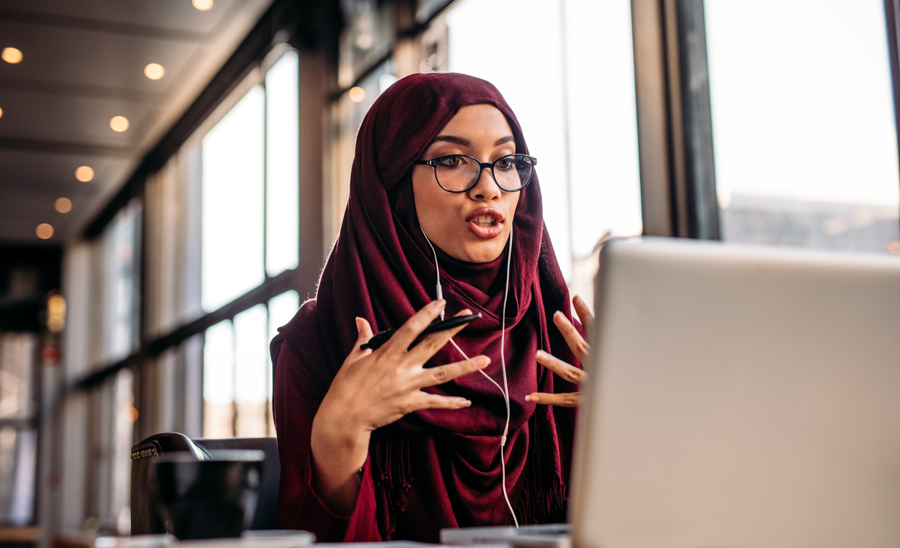 Businesswoman in hijab speaking in teleconference at coffee shop