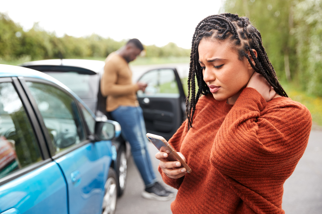 Woman with injured neck calling insurance company after car accident