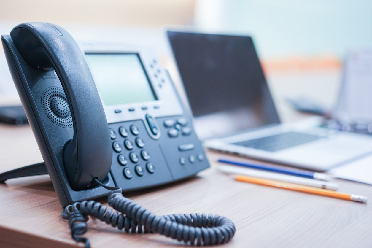 Landline office telephone beside laptop