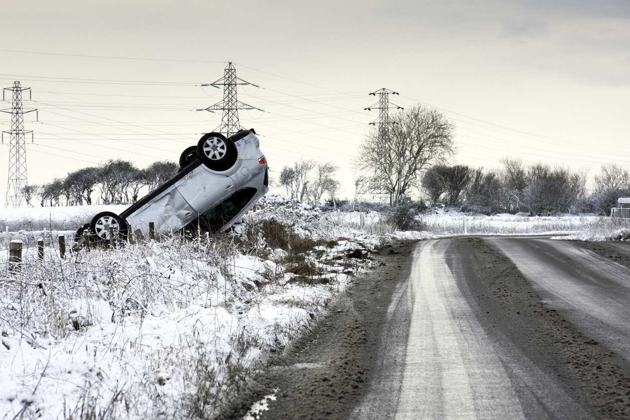 Overturned car beside road in winter