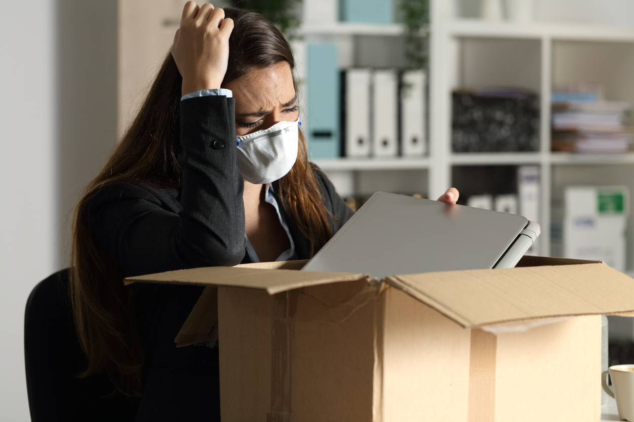 Sacked employee with mask packing her belongings