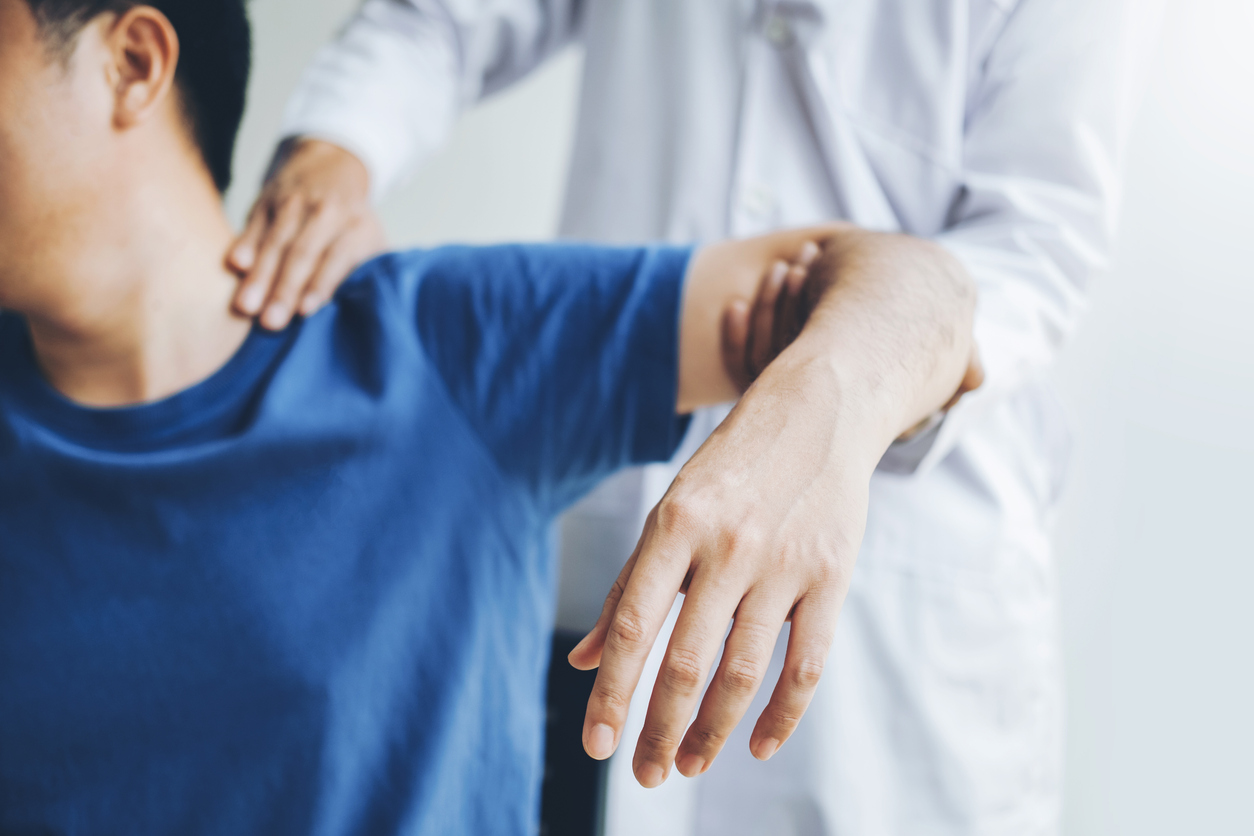 Physiotherapist assisting male patient with his shoulder