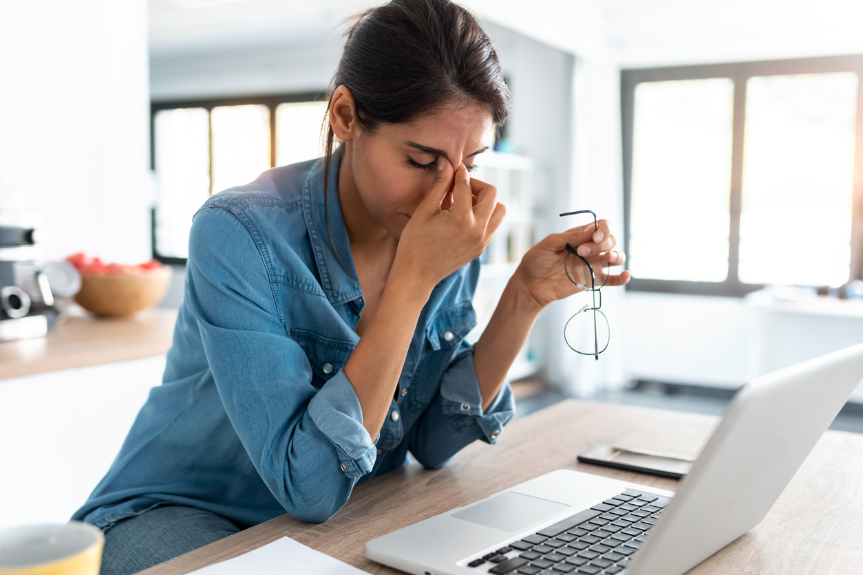 Stressed business woman working from home on laptop looking worried, tired and overwhelmed.