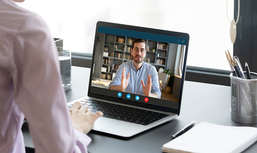 Woman negotiating via internet using laptop, view over female shoulder