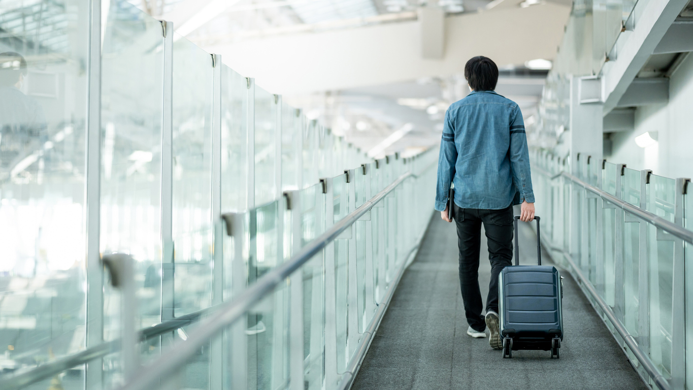 Asian male tourist entering an airport terminal