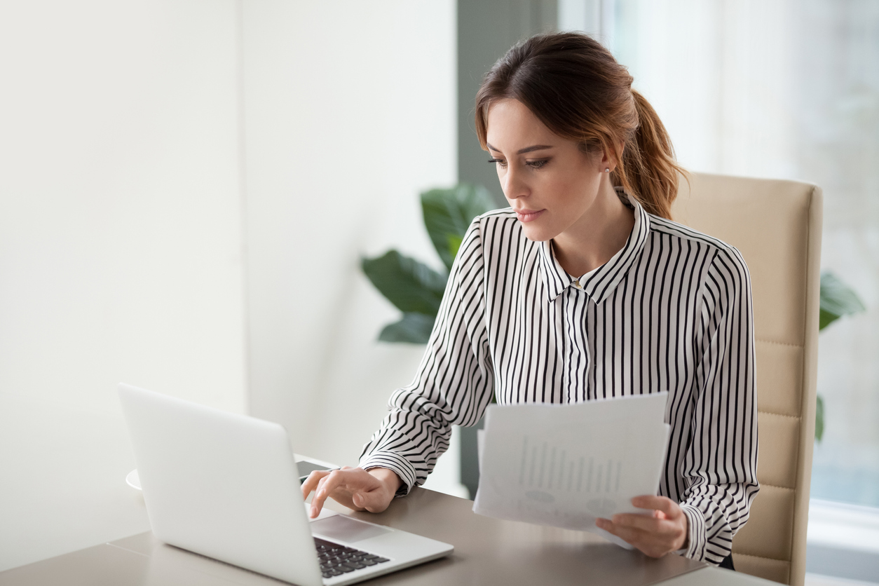 Solicitor typing on laptop and holding documents