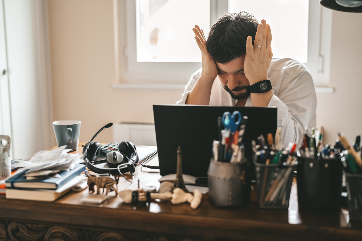 Tired frustrated exhausted businessman working from home online sitting at home office with laptop during quarantine and self isolation period at pandemic. Crisis management. Despair of market falling down.