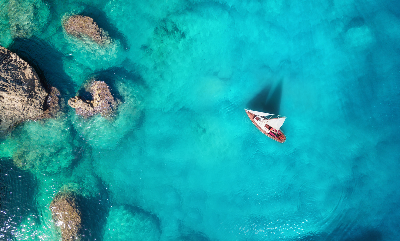 Yacht on the sea from top view. Turquoise water background from top view. Summer seascape from air. Travel concept and idea