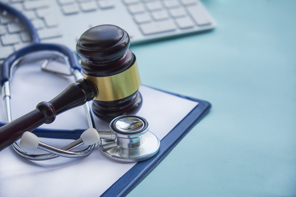 Gavel and stethoscope on medical blue surface