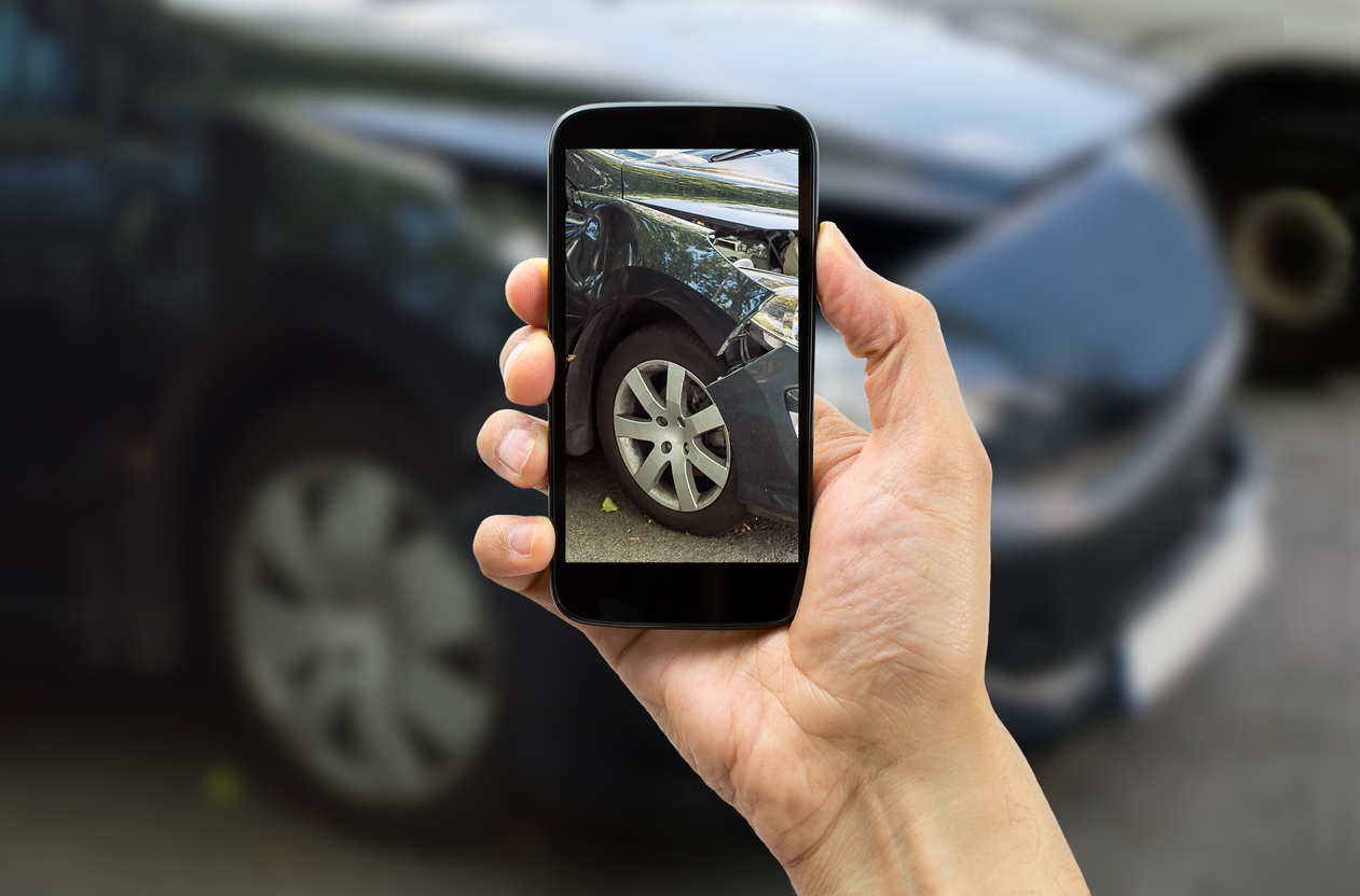 Man taking photo of car accident scene on phone