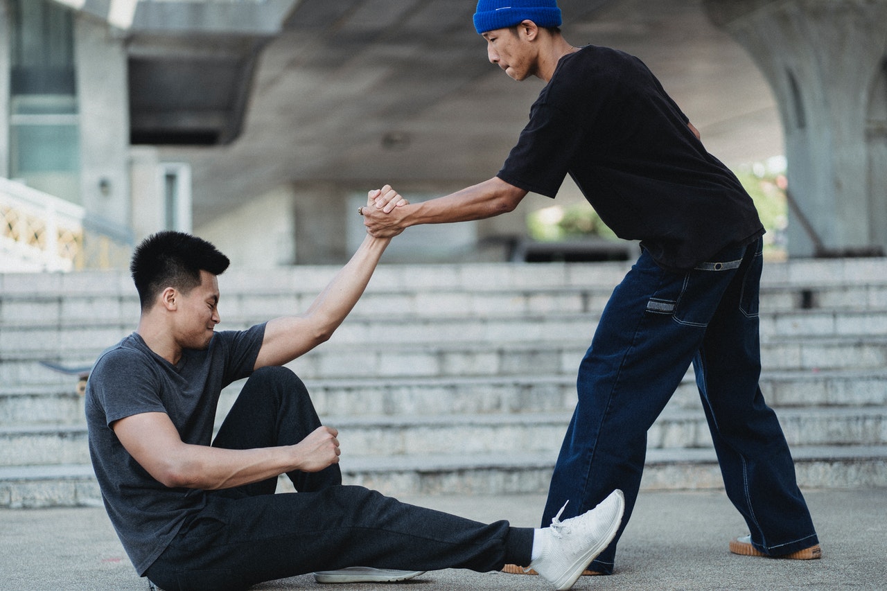 Man helping other man up after slip and fall accident