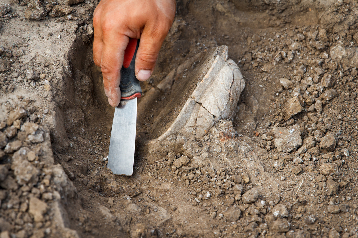 Archaeological excavations, archaeologists work, dig up an ancient clay artifact with special tools