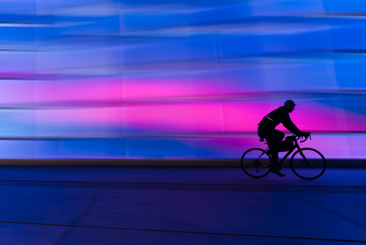 Man riding bicycle next to pink light