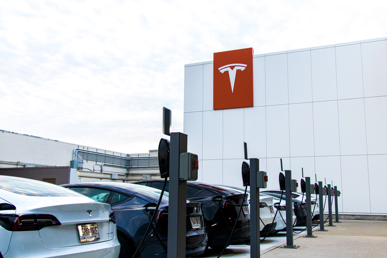 Tesla cars plugged in at a Tesla store parking lot in a shopping mall.