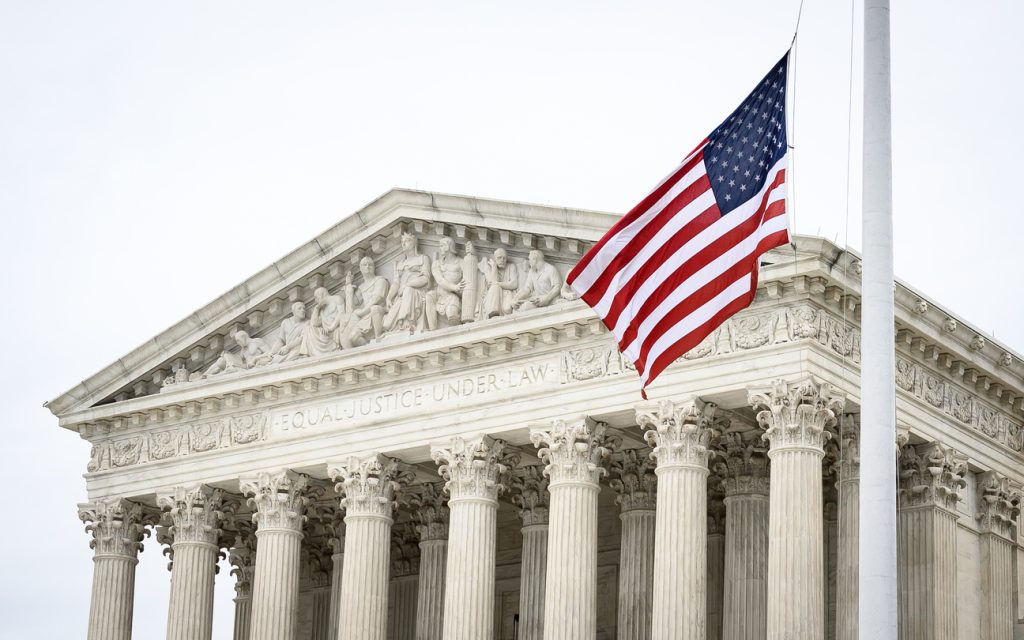 A picture of the supreme court, with the US flag waving in front of the phrase "Equal Justice Under Law"