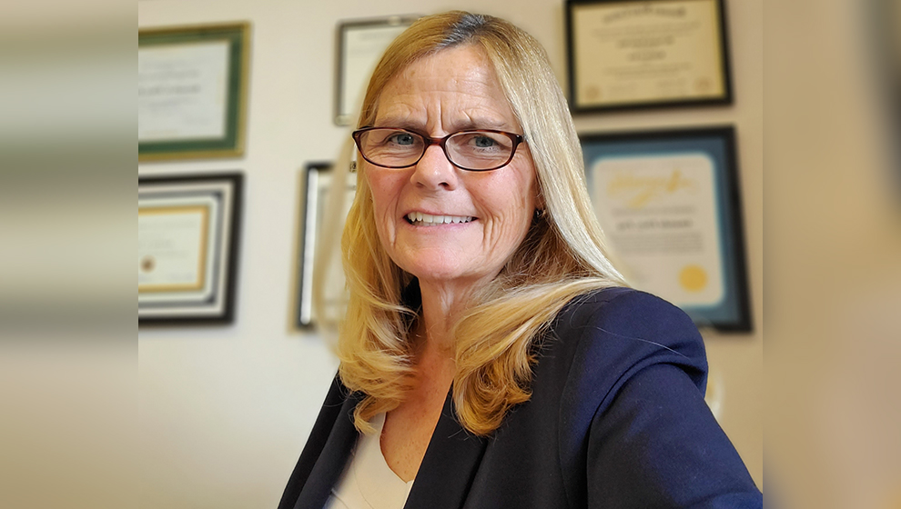 Female estate planning attorney standing in office with certificates.