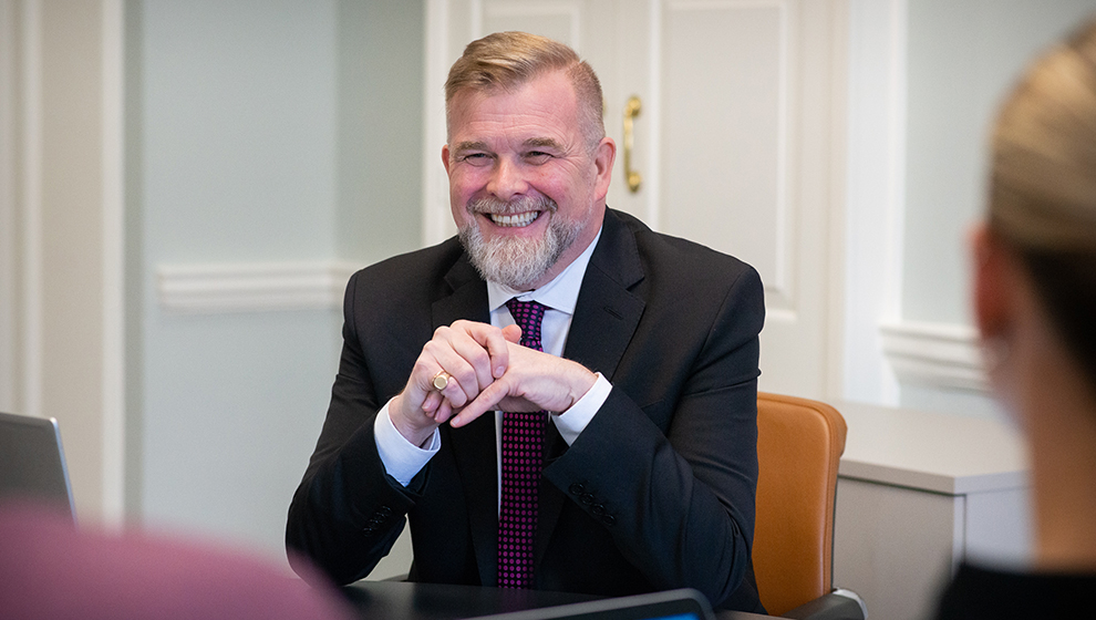 Charity organiser in business suit smiling in meeting room.