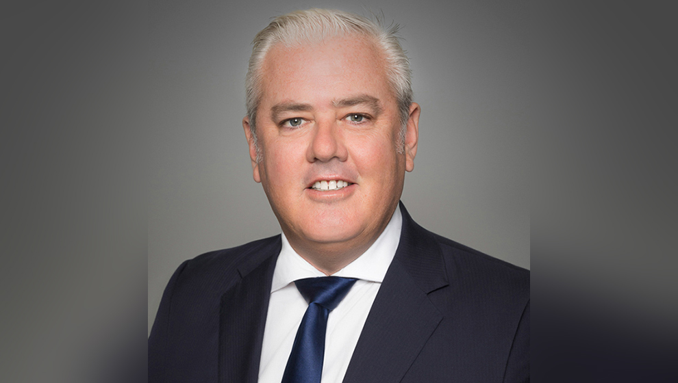 Chartered accountant wearing formal suit in front of plain background