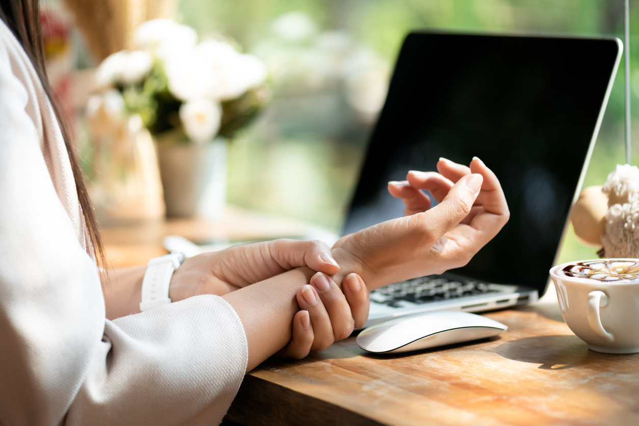 Closeup woman holding her wrist pain from using computer. Office syndrome hand pain by occupational disease.