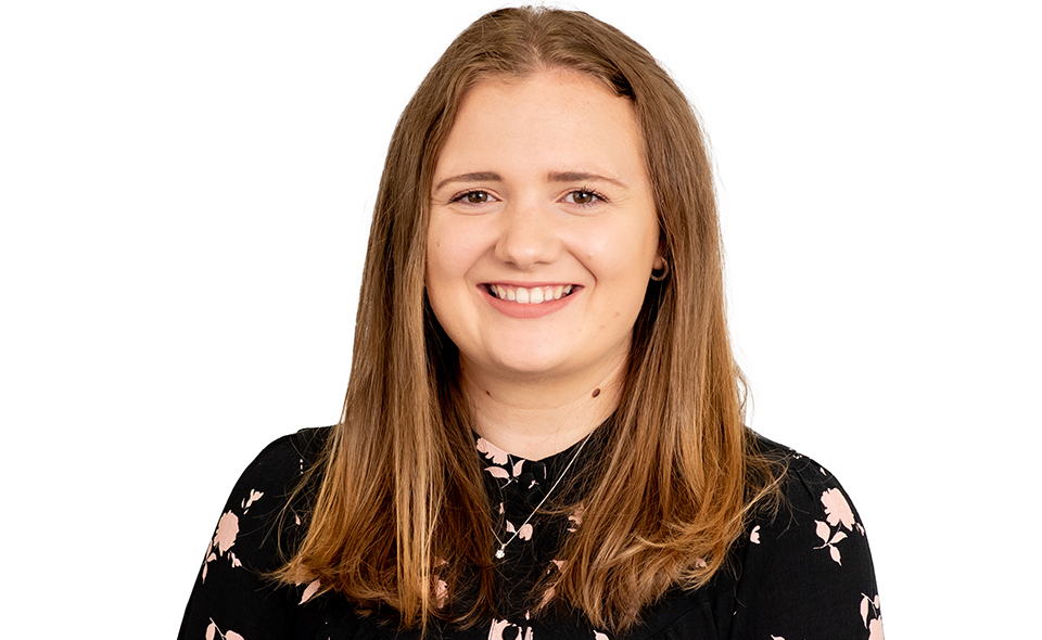 Female commercial solicitor standing in front of white background.