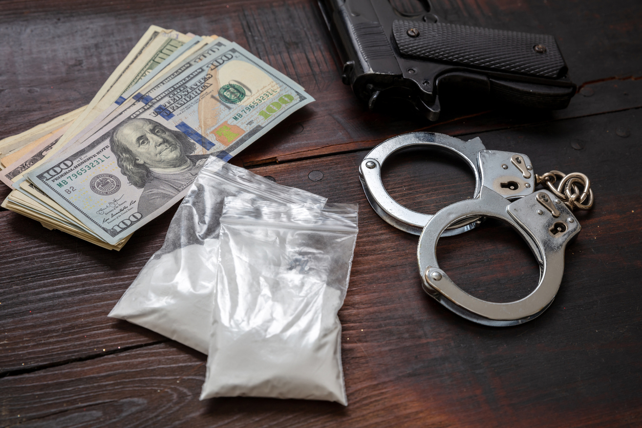 Cocaine plastic packets, pistol US dollars banknotes and handcuffs. Drugs narcotics possesion and use, arrest and punishment for illegal business concept.