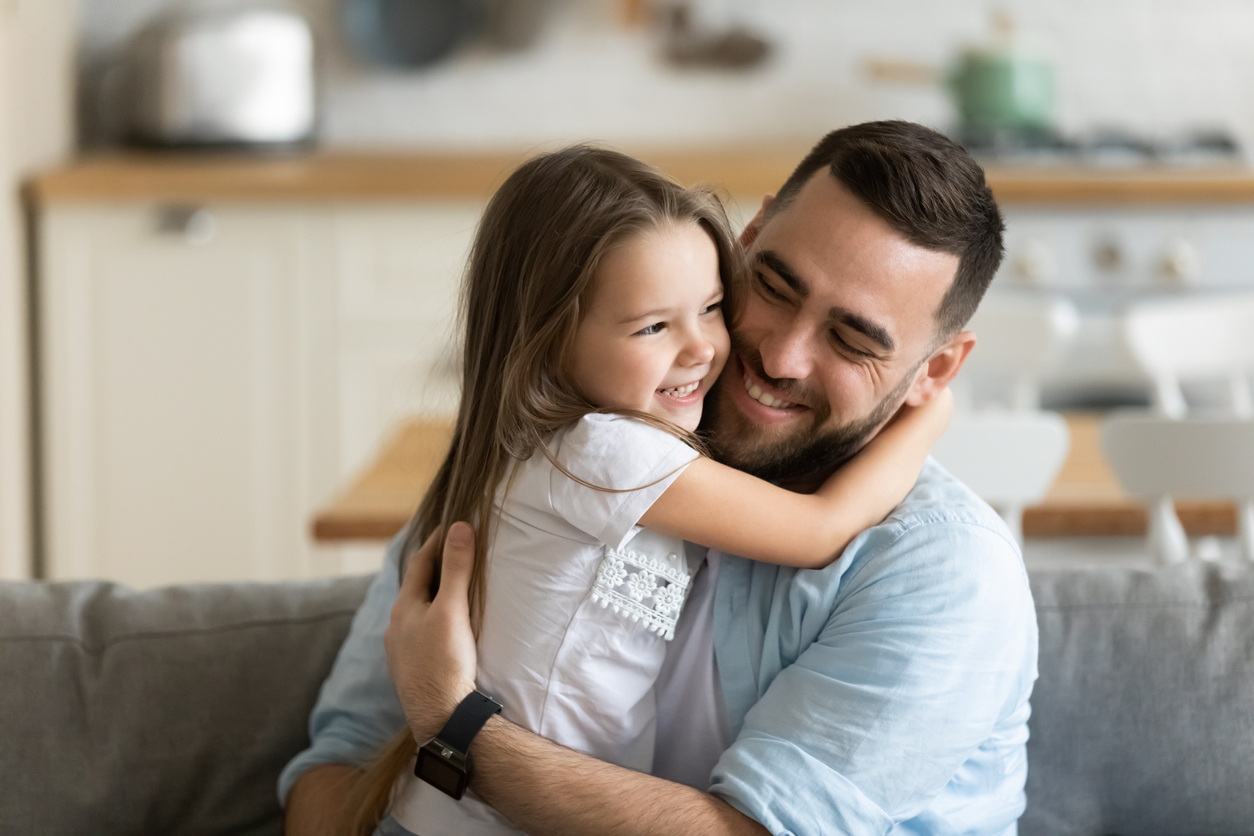 Father hugging daughter on a sofa