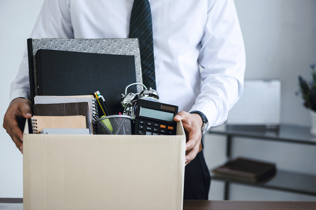 A fired employee gathers his belongings in a box.