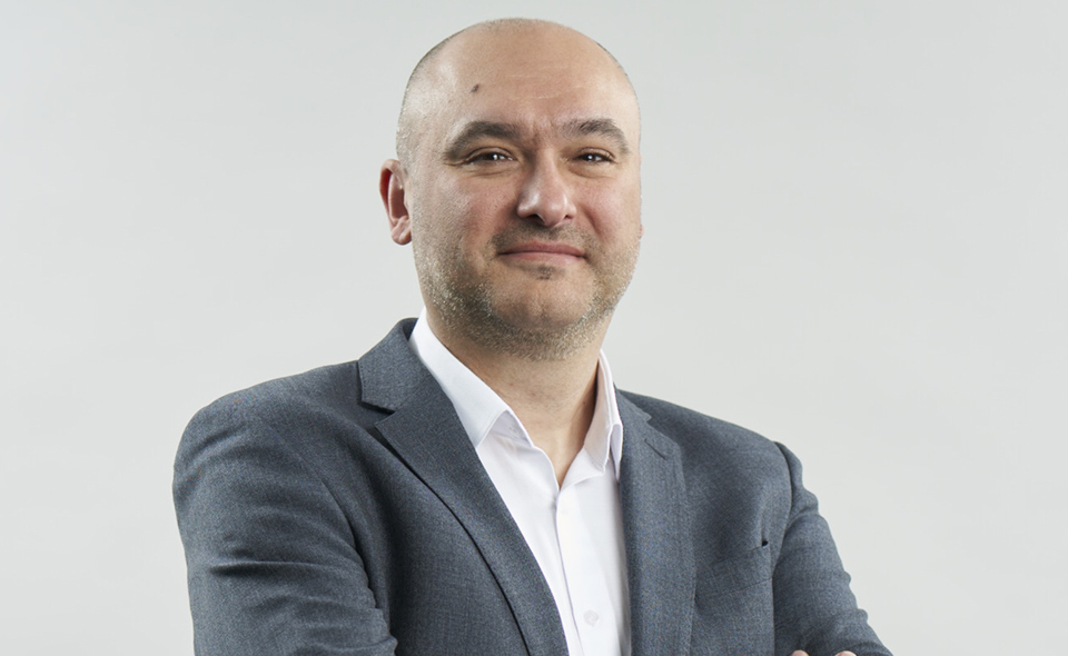 Process optimisation specialist Ilija Ugrinic standing before a grey background.