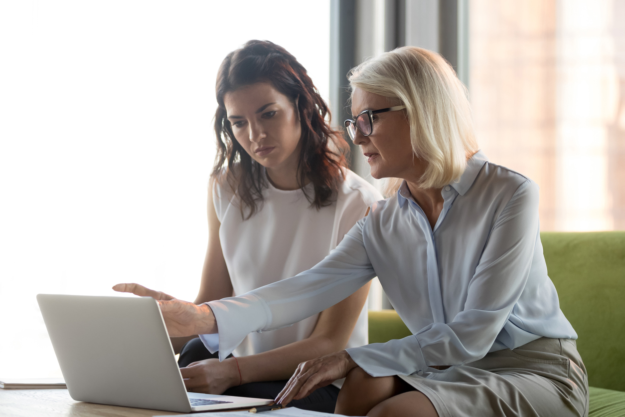 Senior and junior lawyer using a laptop