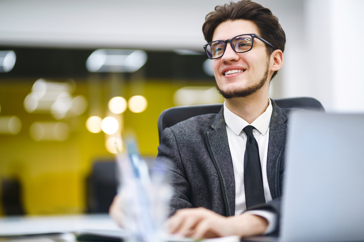 Young office manager working with papers and computer working at office. Businessman writes, reviews and analyze documents, plans. Stylish man in a suit working with new startup project.