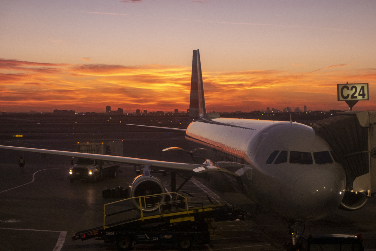 American Airlines Airbus aircraft at Dallas/Fort Worth International Airport gate C24 with sunrise background.