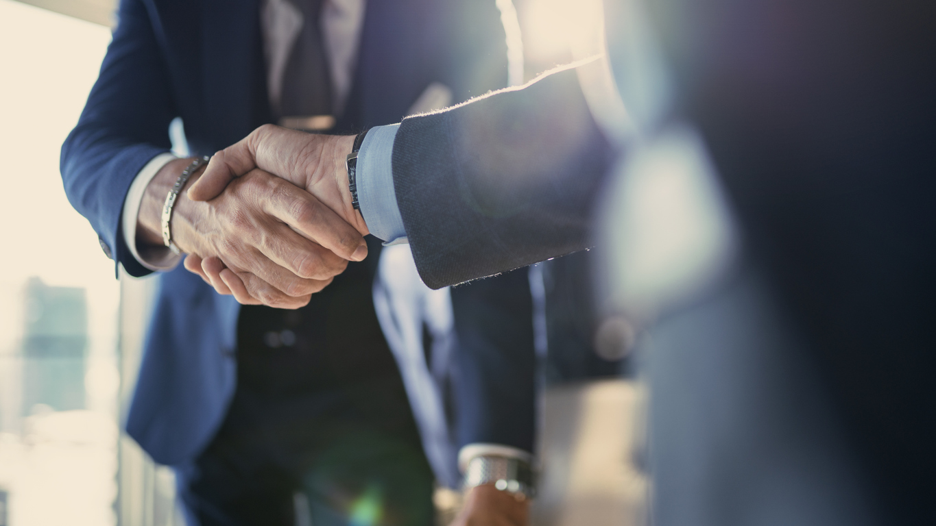 Two male lawyers shake hands in an office environment.