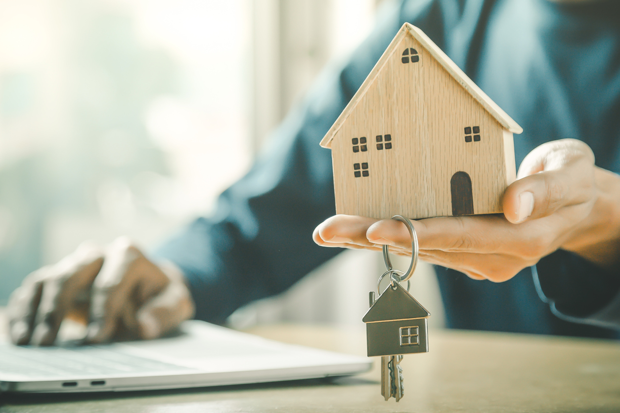 Businessman choosing mini wood house model from model and row of coin money on wood table, selective focus, Planning to buy property. Choose what's the best. A symbol for construction ,ecology, loan concepts.