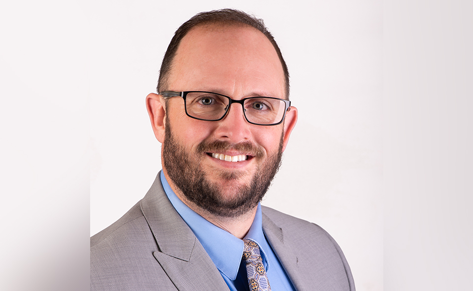 Estate law specialist Elijah Keyes standing in front of a white wall.