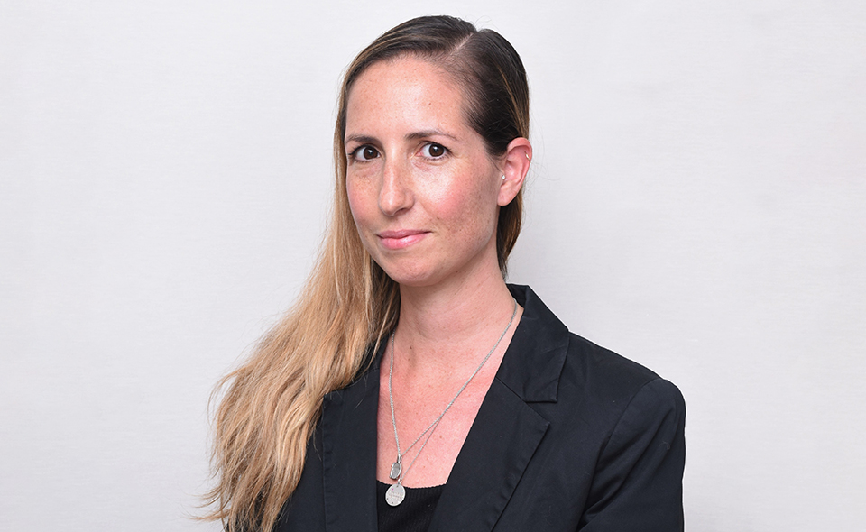 Licensed Israeli attorney Diana Grosz standing in front of a plain wall.