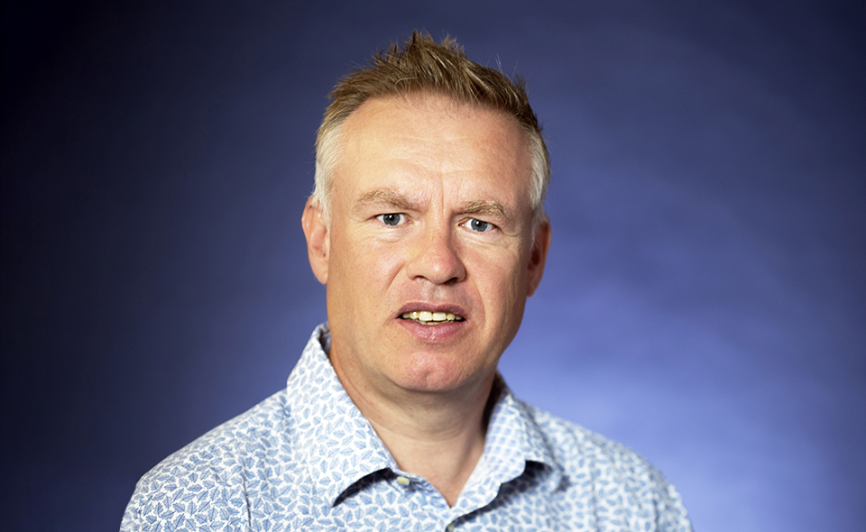 Legal and compliance specialist Jonathan White in front of blue background.