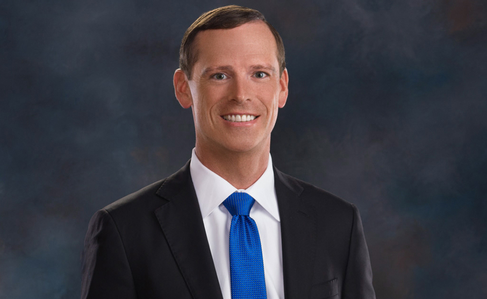 Personal injury specialist Casey Lott standing in front of a dark background.