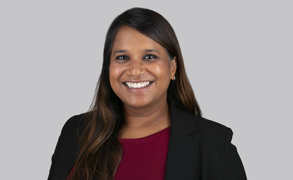 Immigration specialist Malini Skandachanmugarasan standing in front of a plain wall.