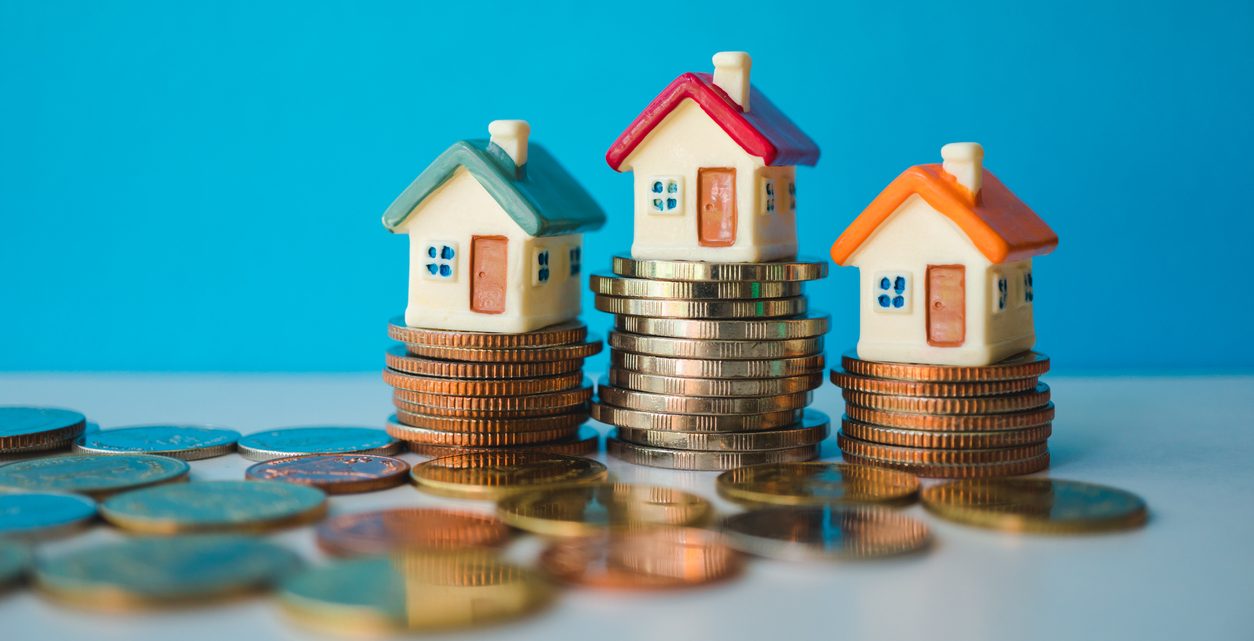 Miniature colorful house with stack coins on blue background using as property and financial concept