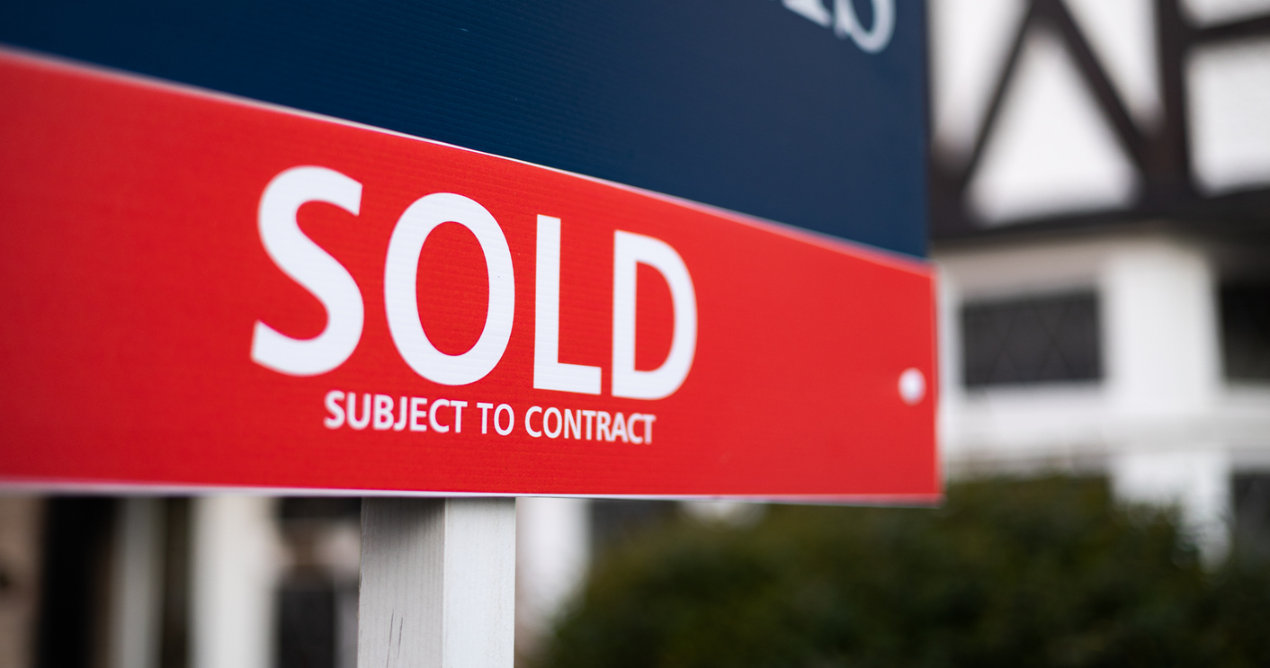 close up of sold sign in front of house - narrow depth of field