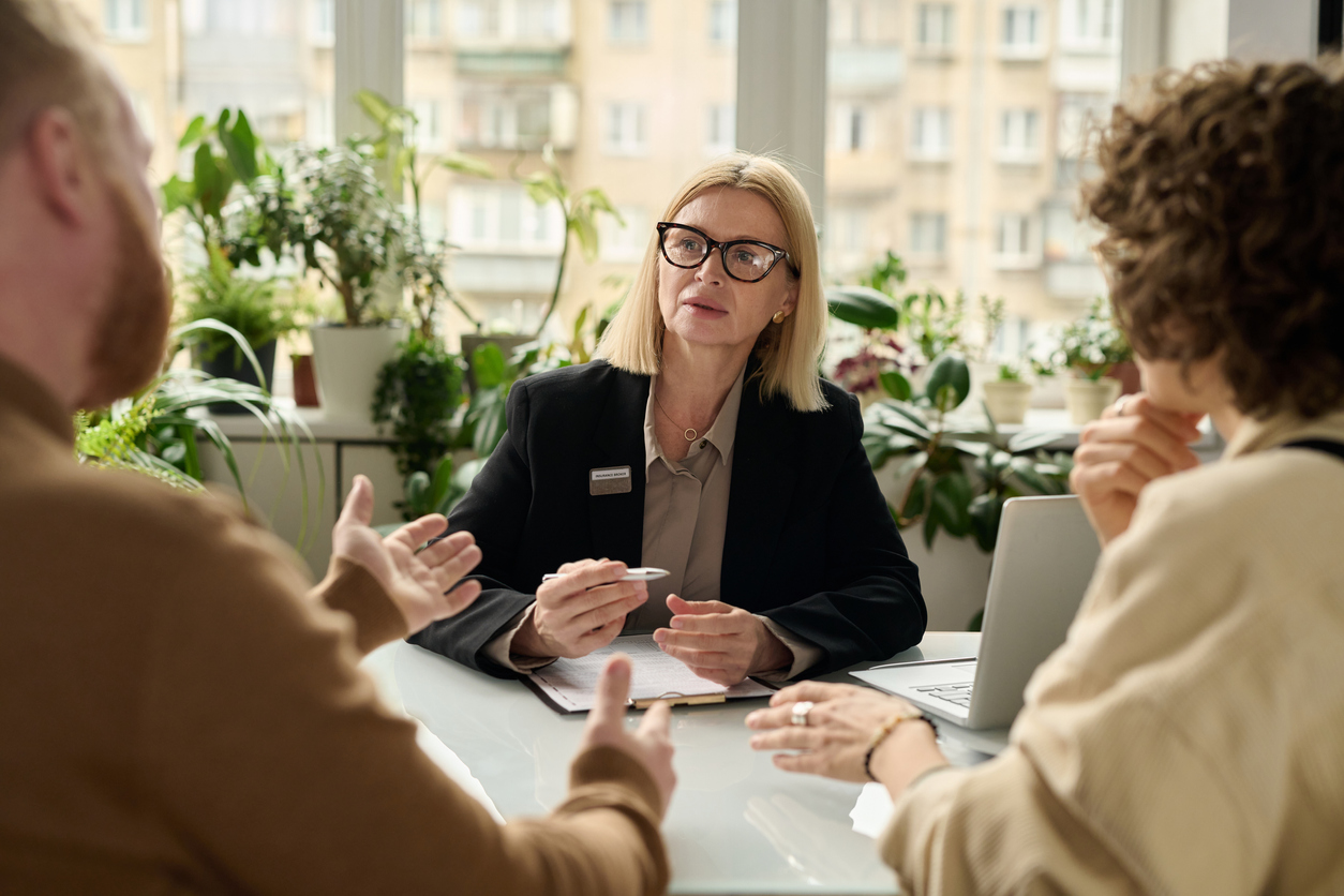 Portrait of mature woman consulting couple in insurance agency office