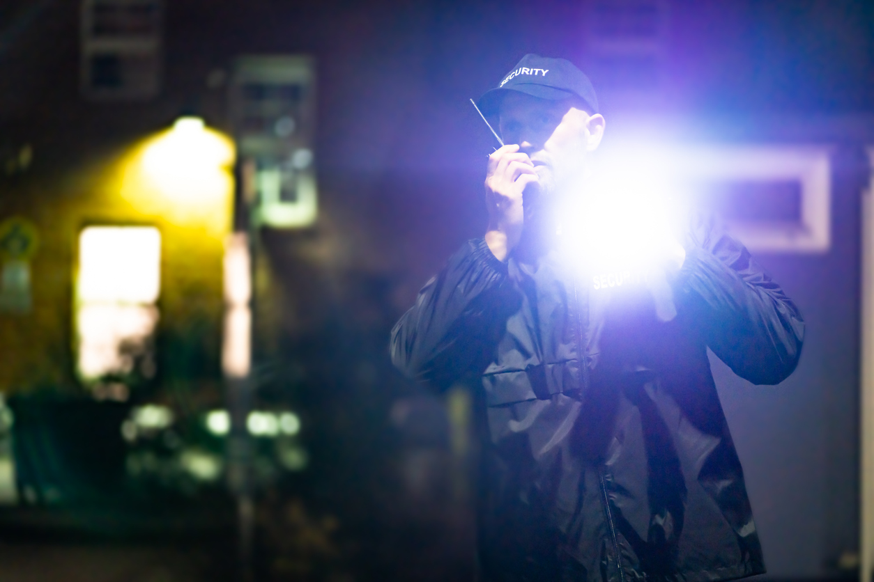 Security Guard Officer Using Walkie-Talkie Radio At Night