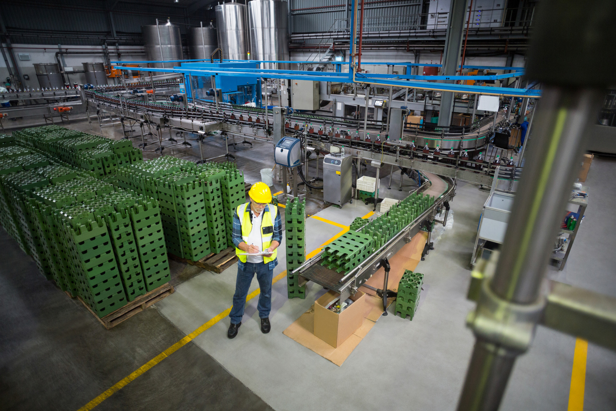 Male factory worker maintaining record on clipboard in drinks production factory