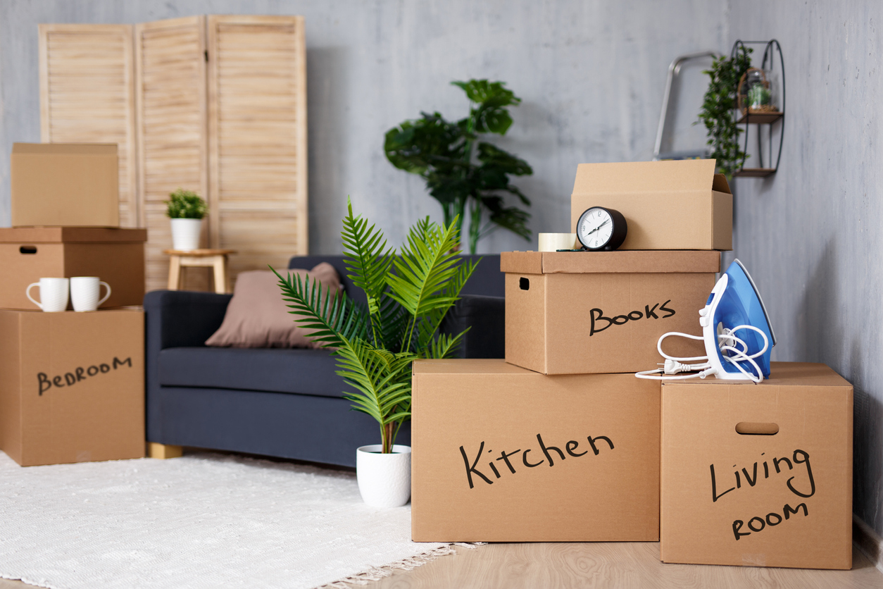 moving to new house - brown cardboard boxes with belongings stacked in living room after moving day