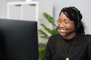 Customer service agent, financial advisor call center employee sits at desk in company in front of computer screen, headphones with microphone on ears, connecting with caller, solving problem